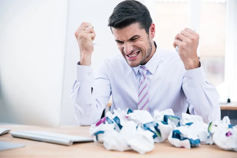 Upset businessman sitting at the table with crumpled paper in office_compressed