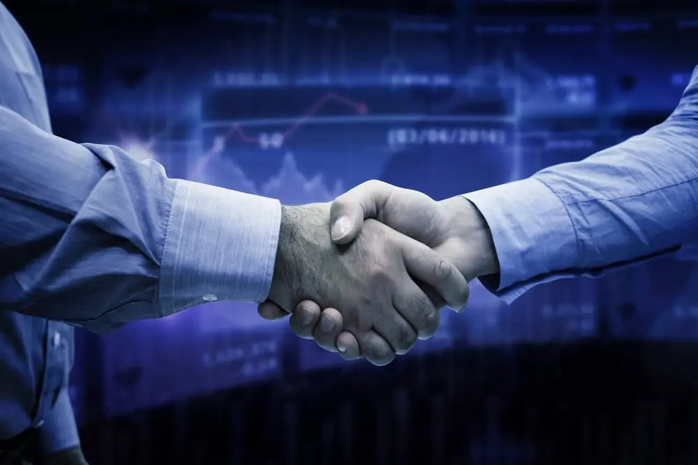 Men shaking hands against stocks and shares_compressed